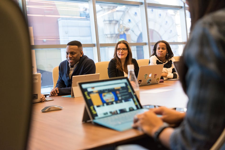 A diverse group of professionals working together on laptops in a modern office meeting room